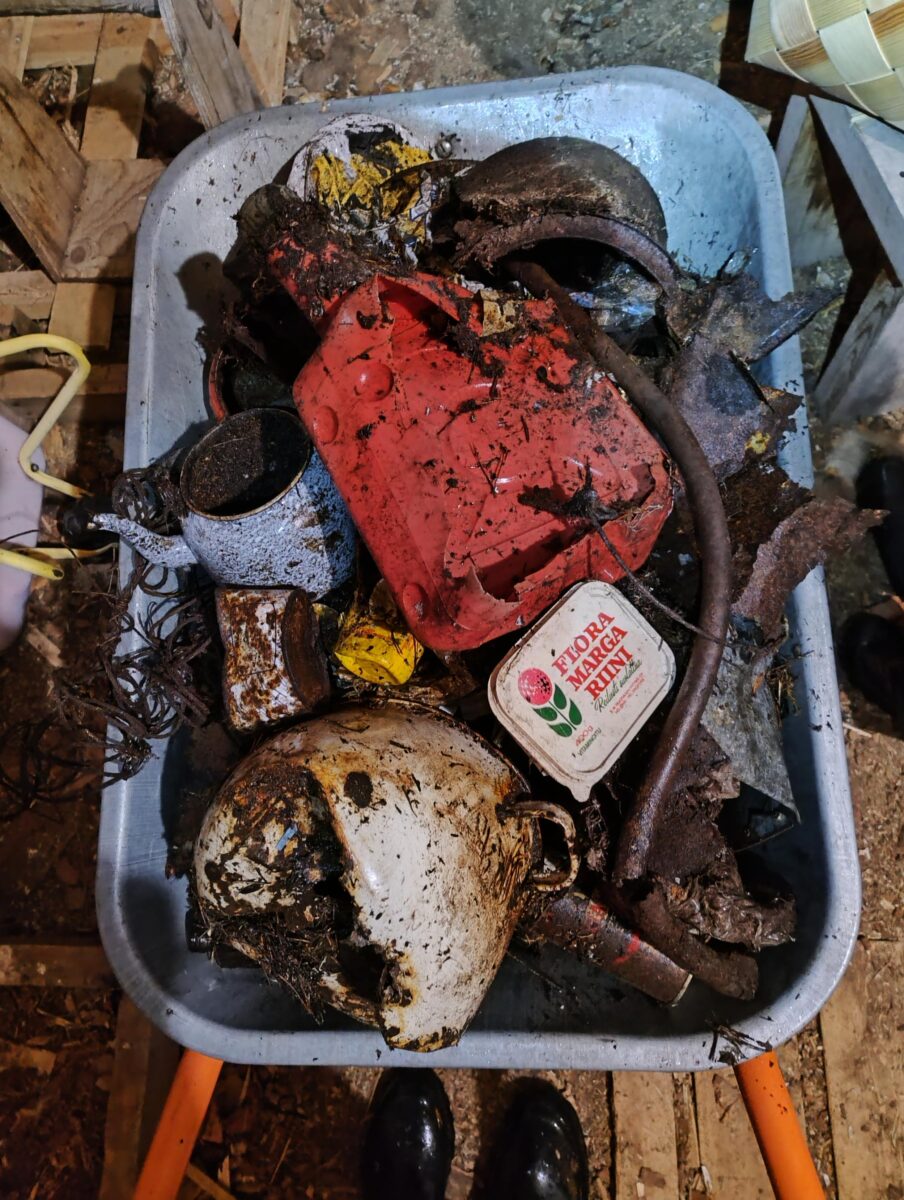 Ylhäältä kuvattu kottikärryllinen sekalaista romua: mm. rikkinäinen kattila, bensakanisteri, teekannu ja Flora-margariinipaketin kansi.